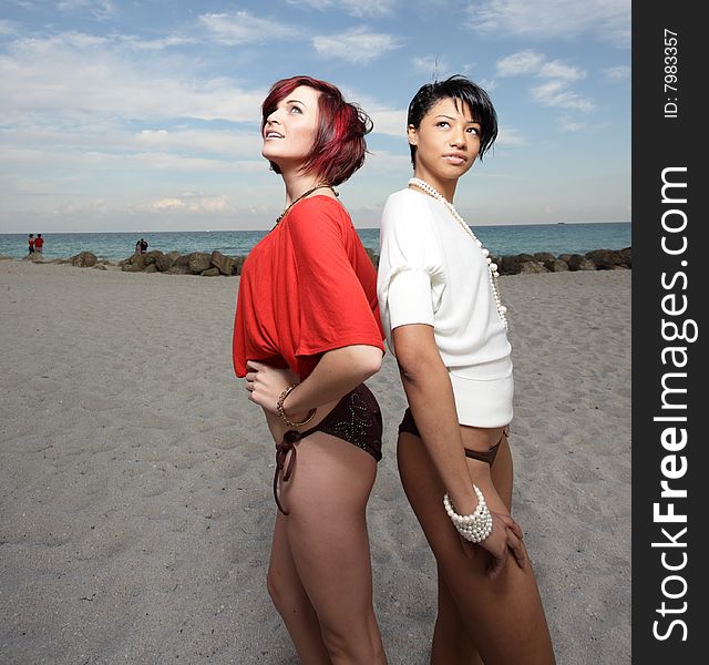 Two beautiful young women on the sand looking at a light from above. Two beautiful young women on the sand looking at a light from above