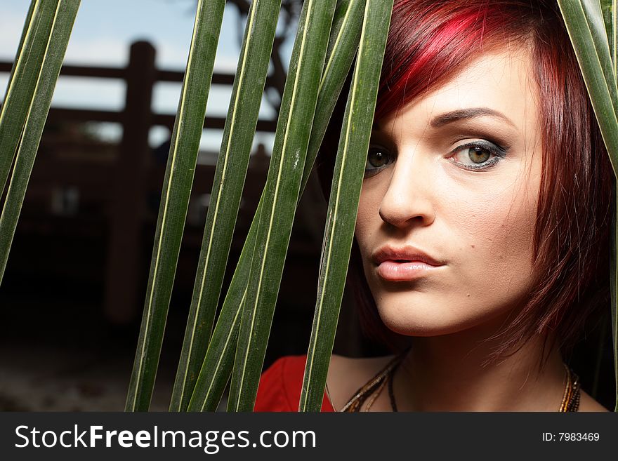 Headshot of a woman posing by green palm fronds. Headshot of a woman posing by green palm fronds