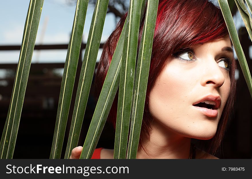 Headshot of a woman posing by green palm fronds. Headshot of a woman posing by green palm fronds
