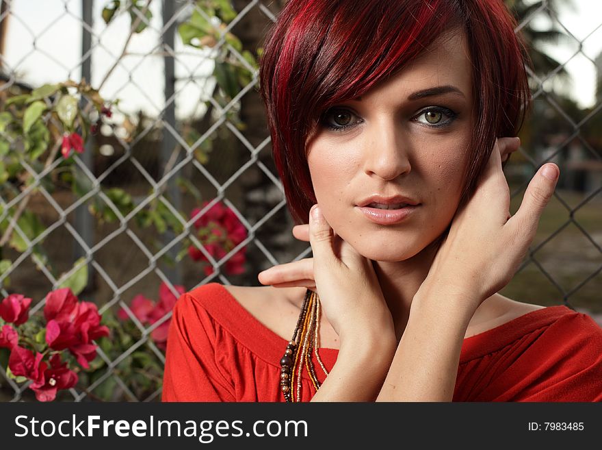 Headshot of a woman posing by a fence. Headshot of a woman posing by a fence