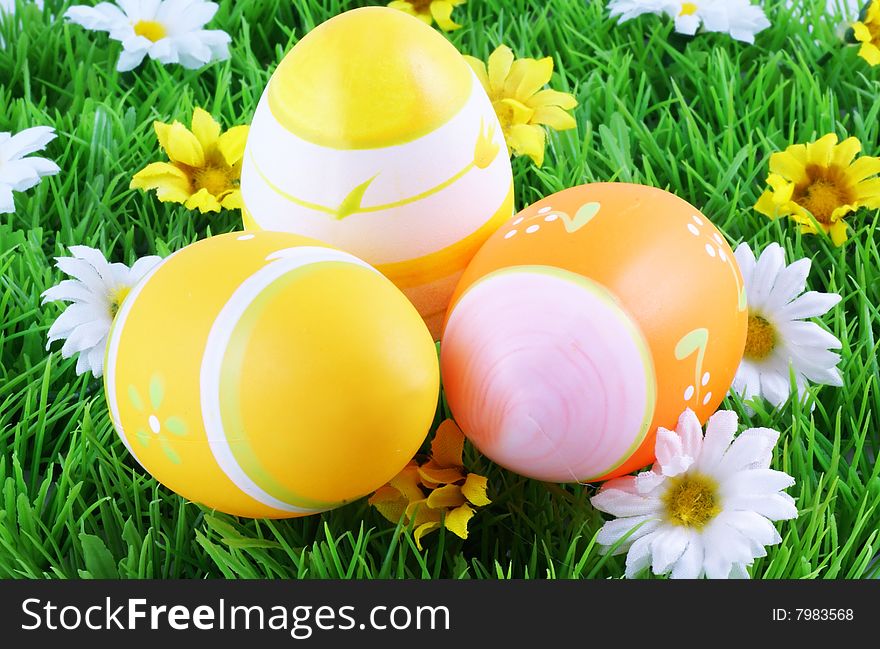 Three easter eggs in grass surrounded by spring flowers. Three easter eggs in grass surrounded by spring flowers.