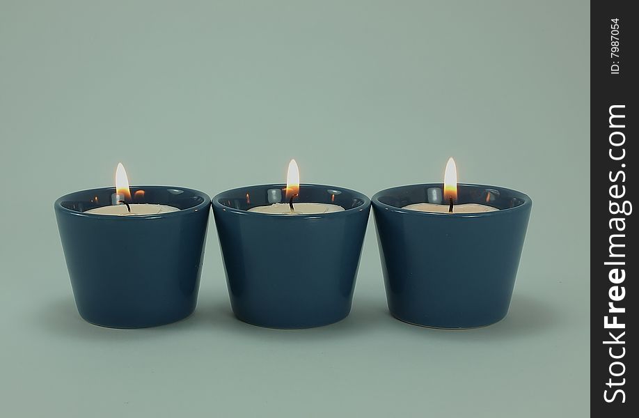 Three lighted candles in blue holder
