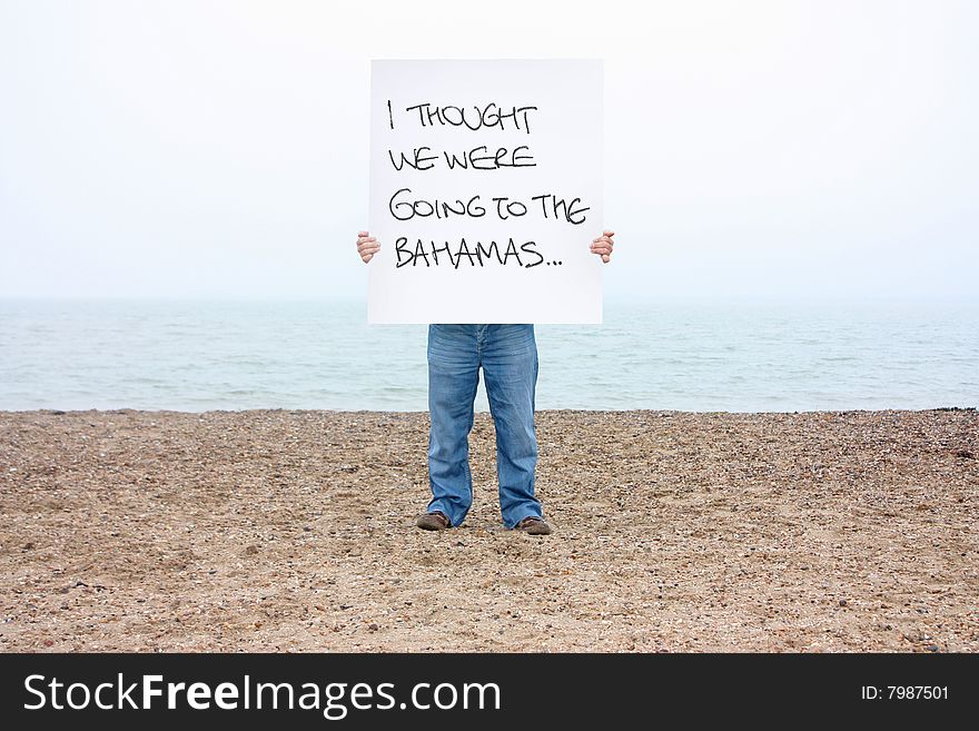 A man holding a sign on a winters beach in the uk. A man holding a sign on a winters beach in the uk