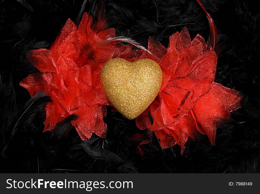 Golden heart with red wings over black feathers background. Golden heart with red wings over black feathers background