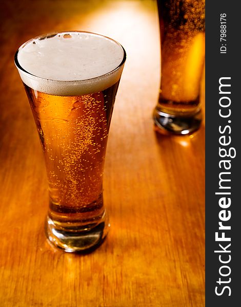 Two beer glasses on wood background, selective focus. Two beer glasses on wood background, selective focus