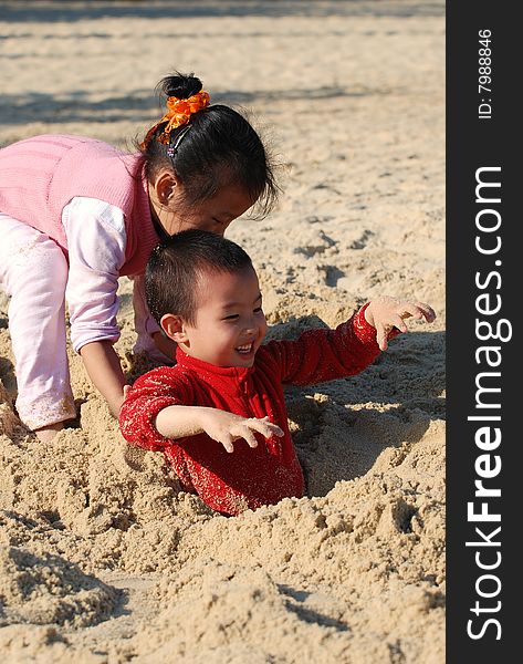 Young Kids Playing Burying Games in the sunny beach