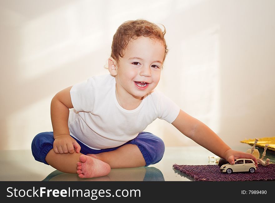 Small boy playing with a toy car on glass table