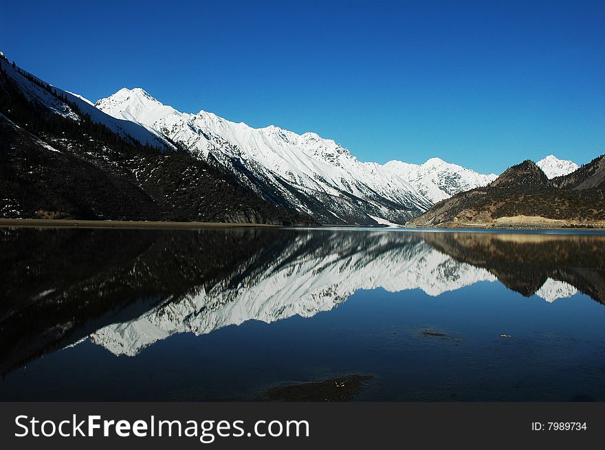 Snow Mountains and their mirror in a lake,Tibet,in a Spring morning. Snow Mountains and their mirror in a lake,Tibet,in a Spring morning