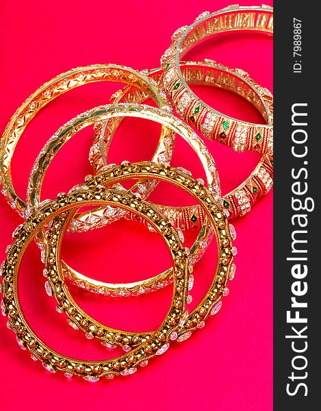 Golden bracelets isolated on colored background.