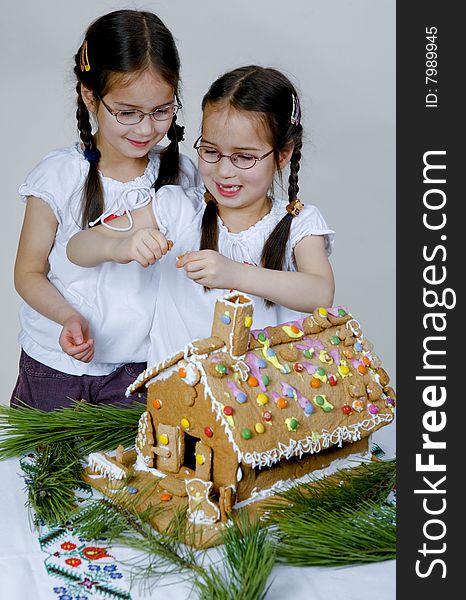 Twins decorating a gingerbread house