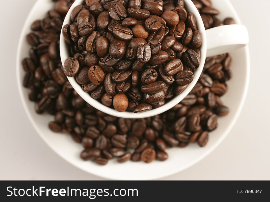 Coffee cup full of coffee beans on white background. Coffee cup full of coffee beans on white background