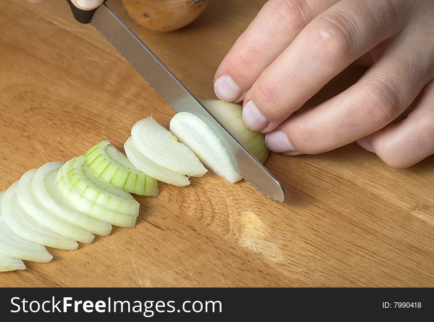 Hands slicing onion on wooden board. Hands slicing onion on wooden board.