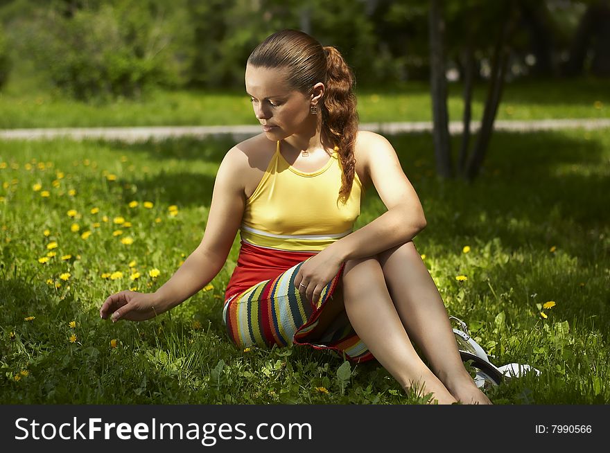 Beautiful Girl Sits On A Green Grass