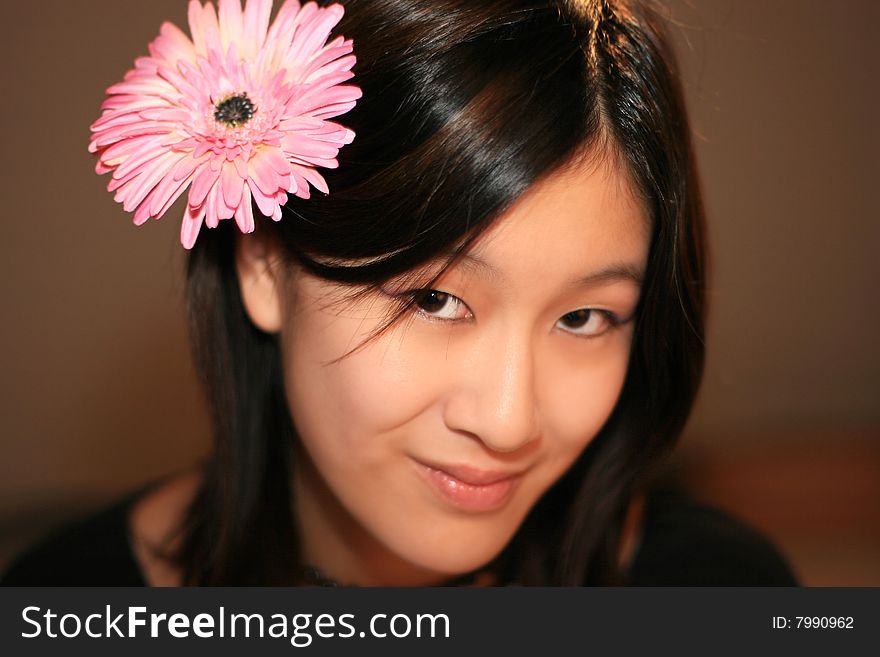 Portrait of a nice fashion asian girl with a pink gerbera flower in her dark hair. Portrait of a nice fashion asian girl with a pink gerbera flower in her dark hair.