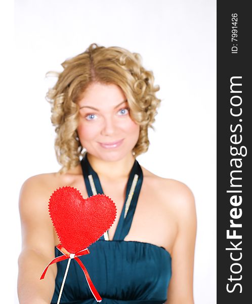 Young blond holding a red heart. Isolated over white. Focus on the heart.