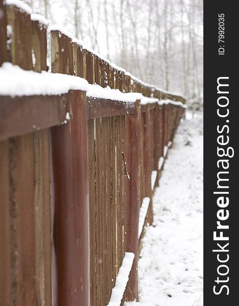 Brown fence under white snow. Brown fence under white snow