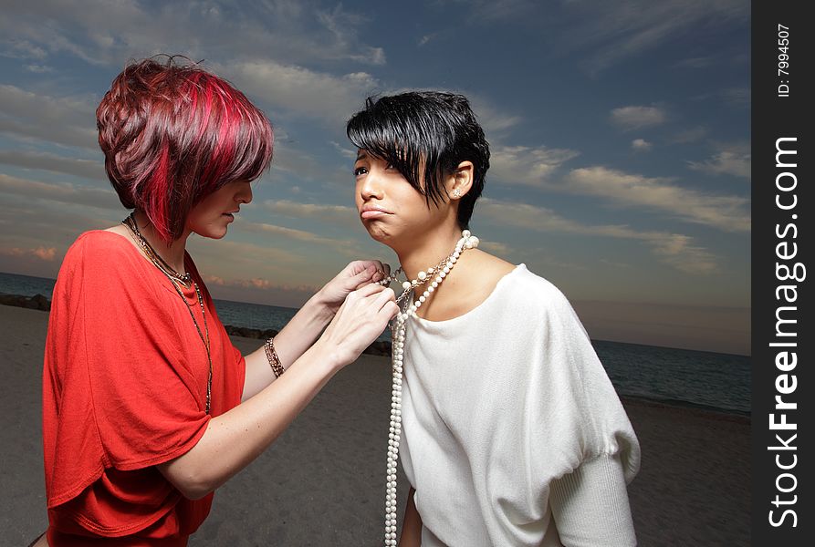 One woman fixing another woman's necklace. One woman fixing another woman's necklace