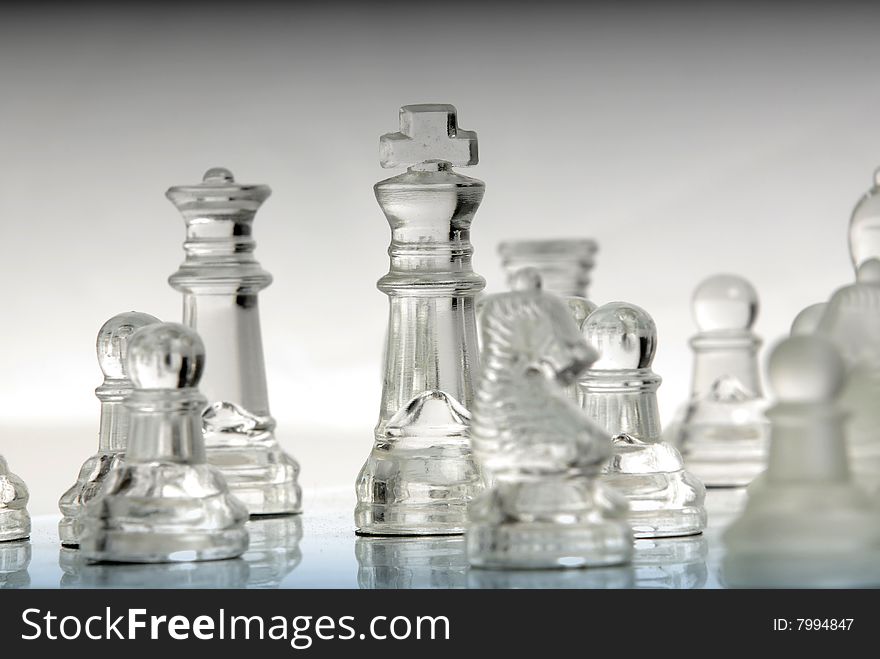 A transparent chess king standing with other pieces on a chessboard