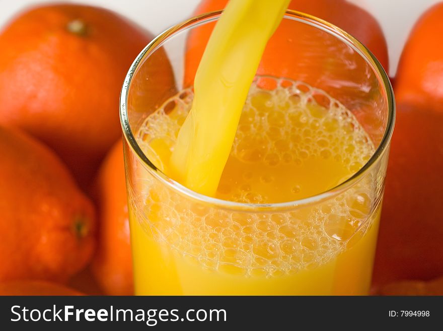 An orange juice pour accompanied by bright mineola oranges. An orange juice pour accompanied by bright mineola oranges