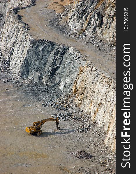 Yellow excavator at the bottom of a  stone pit. Yellow excavator at the bottom of a  stone pit