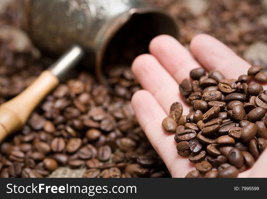 Man hold freshly roasted coffee beans on hand. Shallow depth of field. Focus on hand