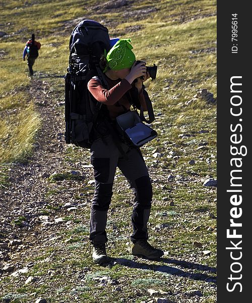 Hiker photographer in funny green bandana making a shot. Hiker photographer in funny green bandana making a shot