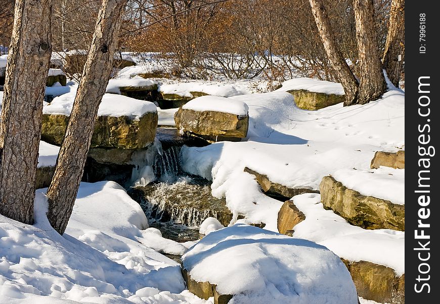 A snowy creek with a small waterfall