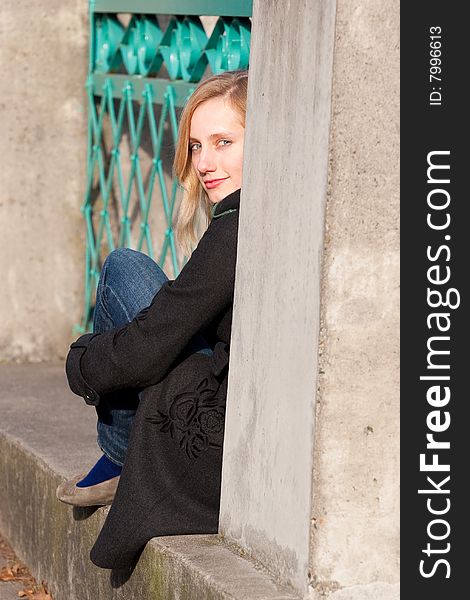 An attractive female model sits on the edge of a cement bridge with a railing. An attractive female model sits on the edge of a cement bridge with a railing.