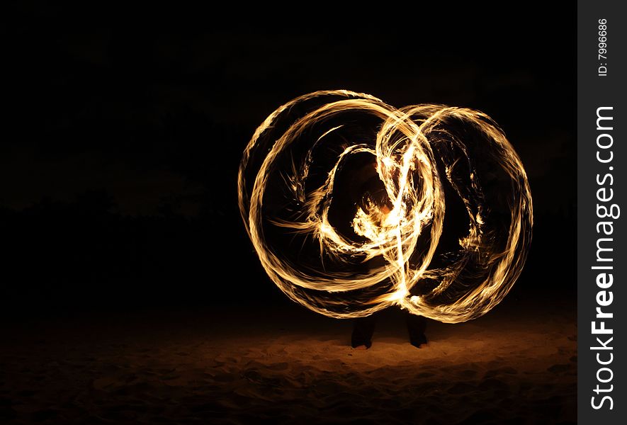 Fire dancer making circles of fire on the beach. Fire dancer making circles of fire on the beach