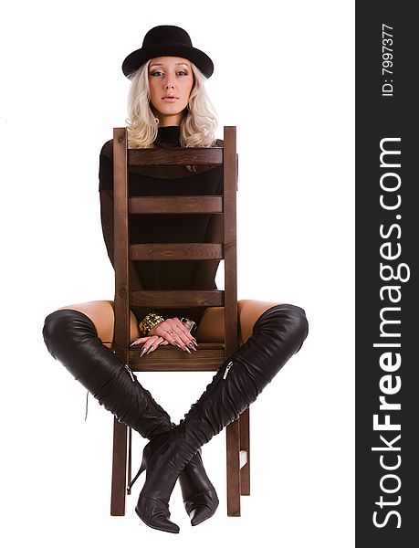 Young attractive blonde woman with black hat and boots sitting in chair. Young attractive blonde woman with black hat and boots sitting in chair