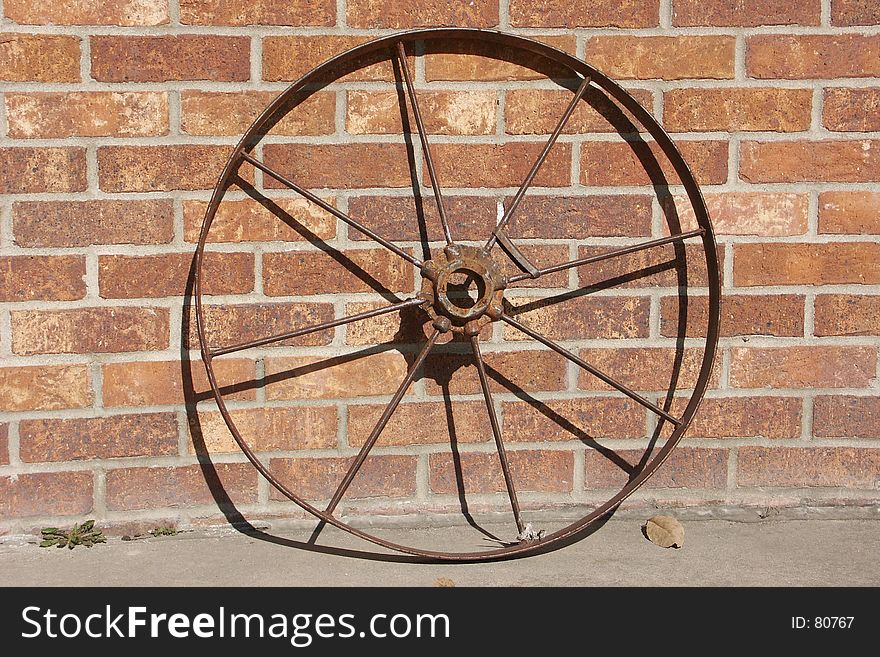 Old iron wheel leaning on a brick wall. Old iron wheel leaning on a brick wall