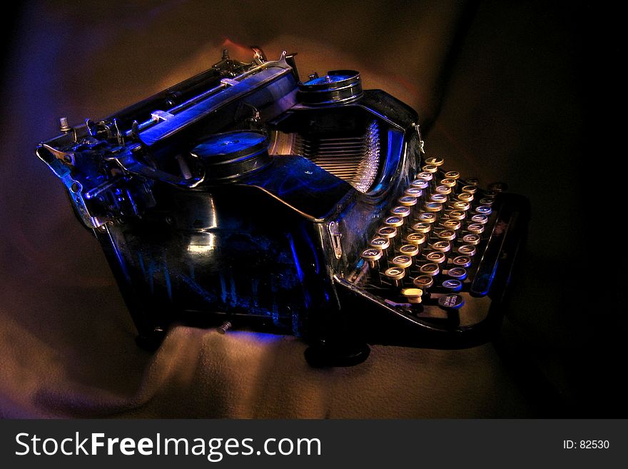 Antique black typewriter painted with UV light. Various objects on a dark background. Artistic blur. Antique black typewriter painted with UV light. Various objects on a dark background. Artistic blur.