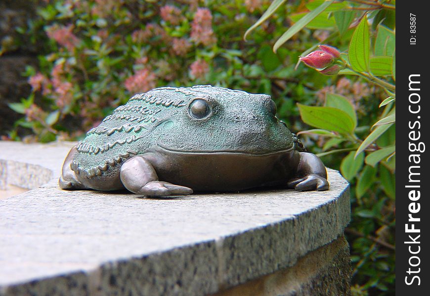 Frog statue sitting on a ledge.