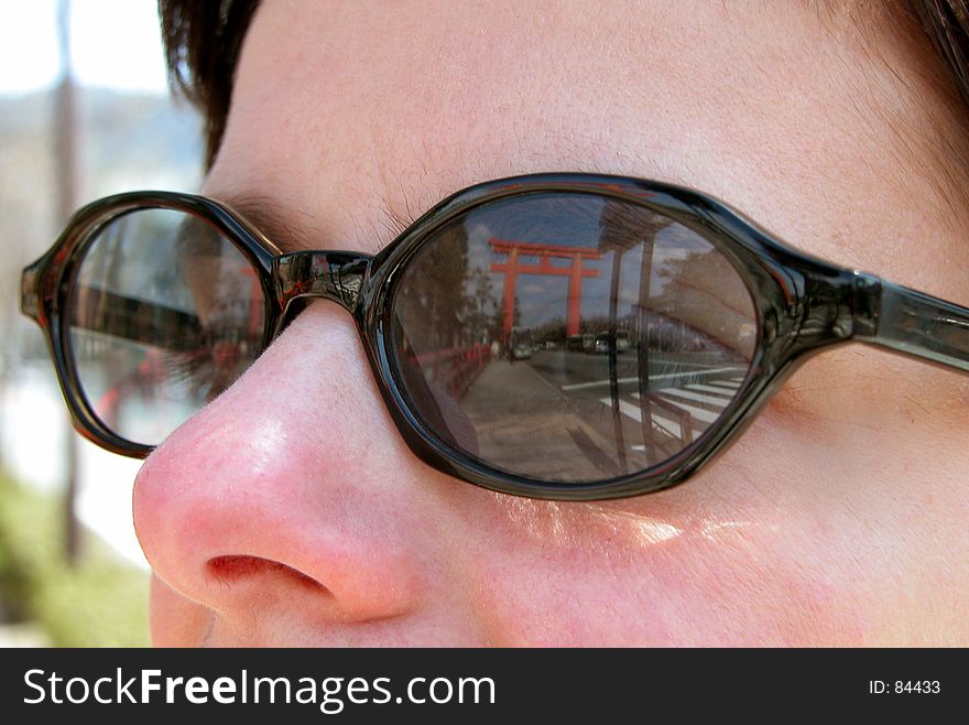 Reflection of a big Japanese temple gate in a tourist woman sunglasses
