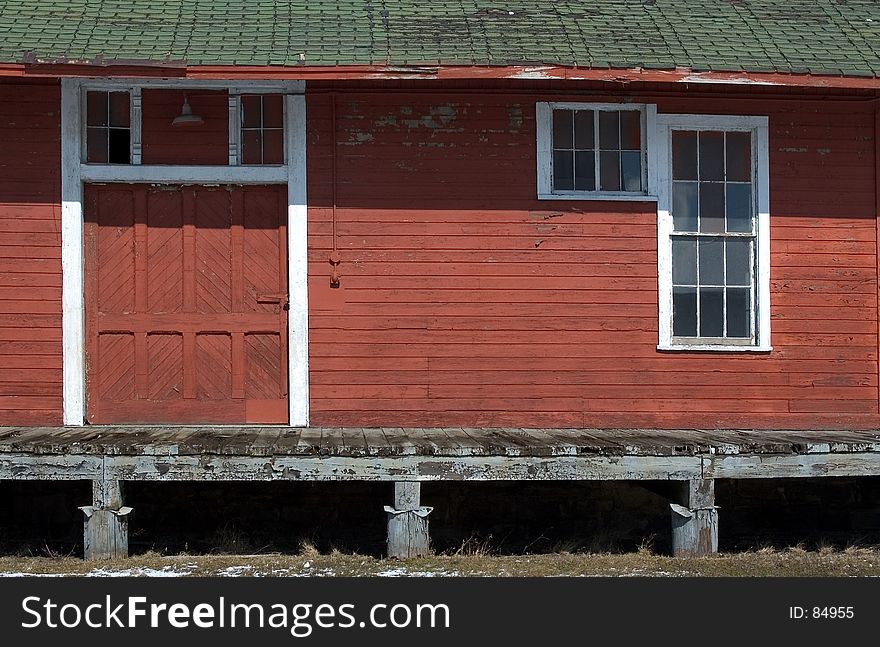 An old platform for unloading trains into the rail stop. Building is painted red with white trim. Dock door and a window are shown in photo. An old platform for unloading trains into the rail stop. Building is painted red with white trim. Dock door and a window are shown in photo.