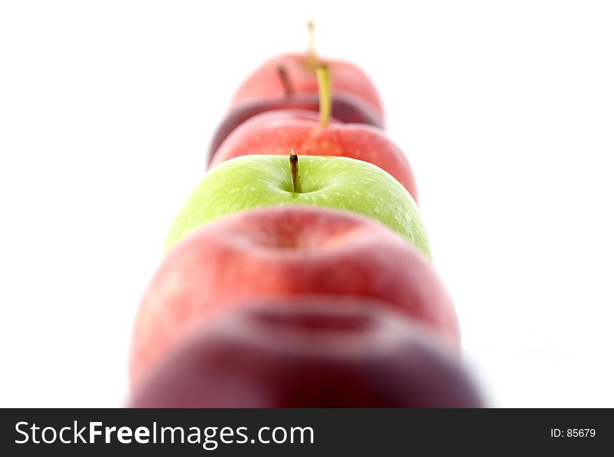 A green apple in a line of red. A green apple in a line of red