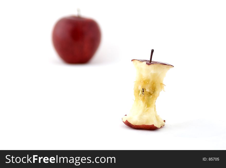 An apple core with an out of focus apple in the background