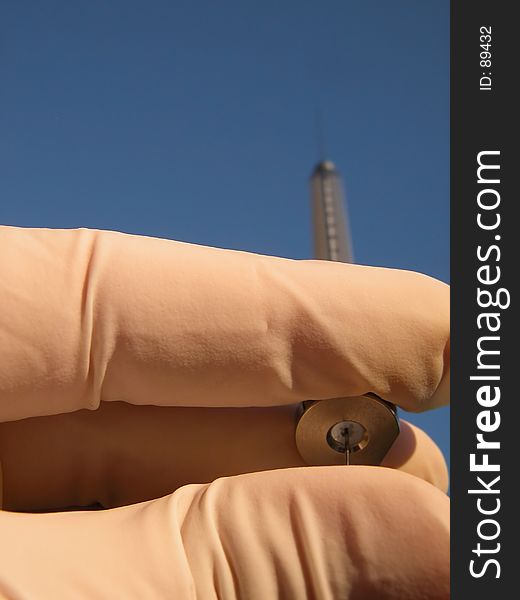 Close up of hand holding a syringe directed toward a blue sunny sky. Hand is protected with white glove, focus on the fingers. Possible use in: environmental protection, succes, aspiration, endeavour... or any websites/catalogs related to chemistry/medical design. Close up of hand holding a syringe directed toward a blue sunny sky. Hand is protected with white glove, focus on the fingers. Possible use in: environmental protection, succes, aspiration, endeavour... or any websites/catalogs related to chemistry/medical design