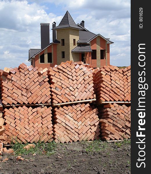 Stacked bricks and built house on the background