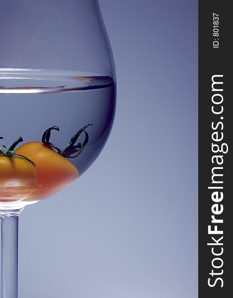 Close up of tomato inside the wine glass. soft lightning is grey+blue background