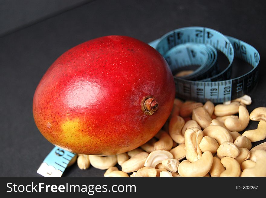 This is an image of mango, measuring tape and cashew nuts. (Please let me know where the image will be used by leaving a message in the Comments Section/See Portfolio). This is an image of mango, measuring tape and cashew nuts. (Please let me know where the image will be used by leaving a message in the Comments Section/See Portfolio)