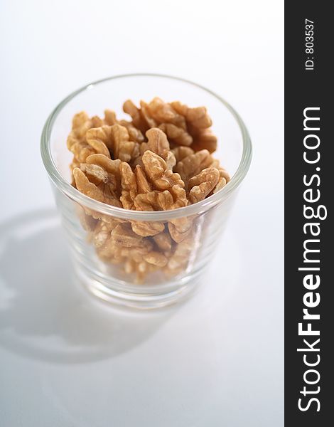 A glass full of crackes walnuts. A glass full of crackes walnuts