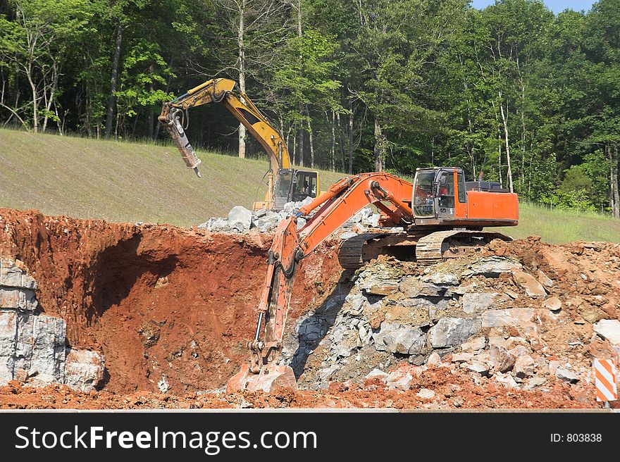 Large trackhoe & hydraulic jack hammer breaking up rock and removing it to make way for new highway. Large trackhoe & hydraulic jack hammer breaking up rock and removing it to make way for new highway