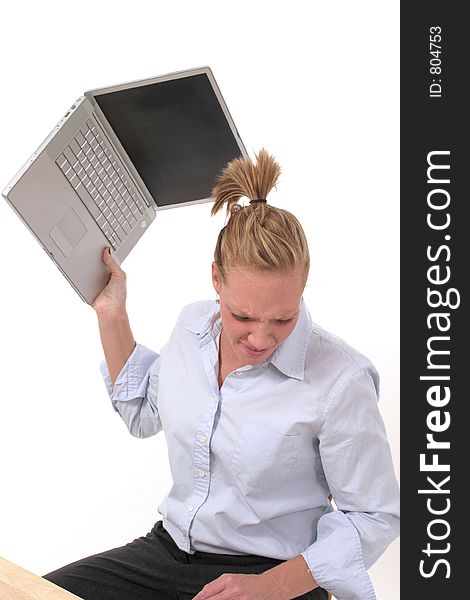 Grimacing and possibly frustrated young business woman seriously considering throwing her laptop computer. Grimacing and possibly frustrated young business woman seriously considering throwing her laptop computer