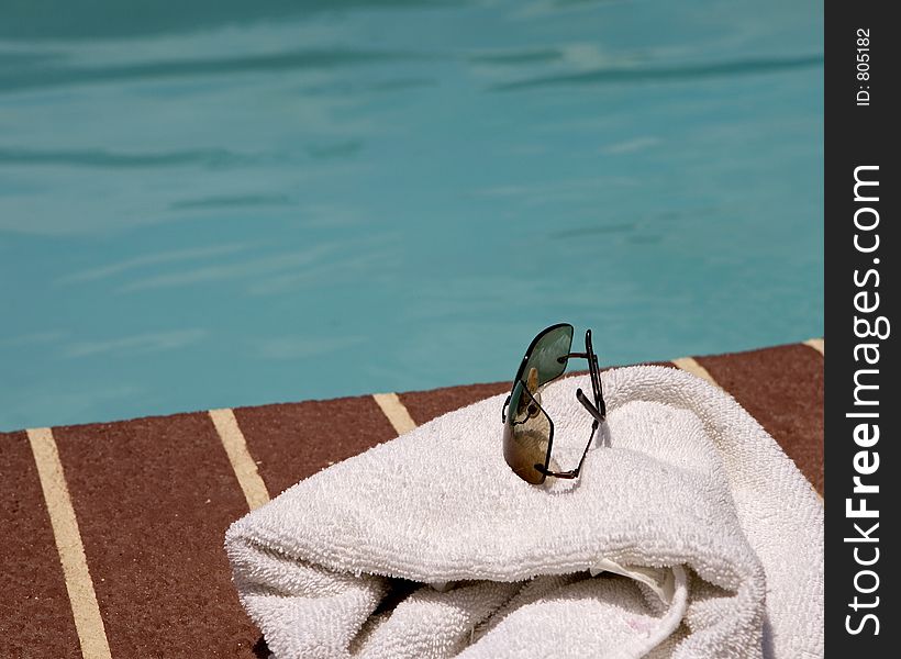 Sun glasses and towel beside a pool. Sun glasses and towel beside a pool