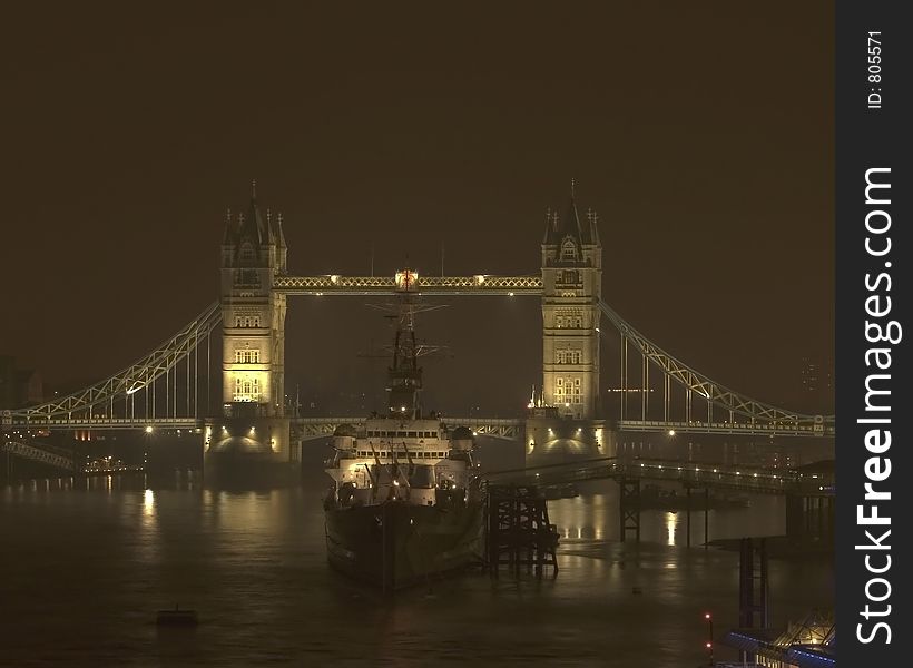 A night view of the Tower Bridge in London with a battleship sittin in front. A night view of the Tower Bridge in London with a battleship sittin in front