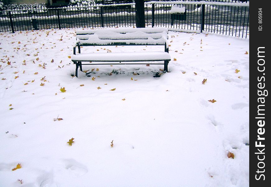 A snow covered bench in a Boston park following an early storm. Boston, MA
