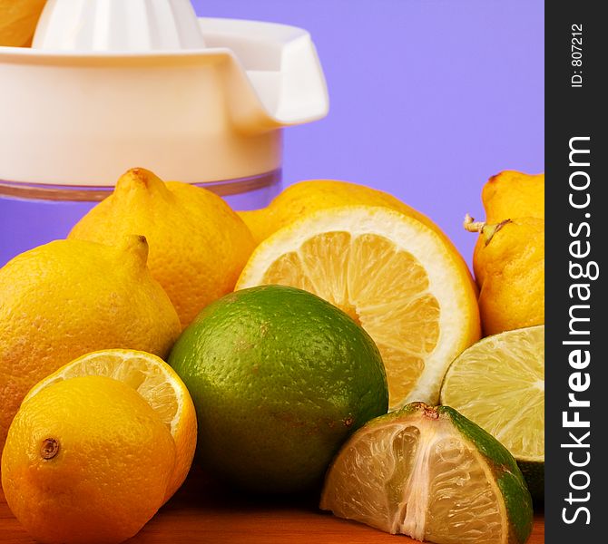 A colorful display of Lemons and limes, in front of a juicer, some cut and some whole. A colorful display of Lemons and limes, in front of a juicer, some cut and some whole.