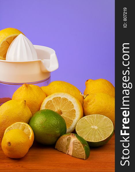 A colorful display of Lemons and limes, in front of a juicer, some cut and some whole. A colorful display of Lemons and limes, in front of a juicer, some cut and some whole.