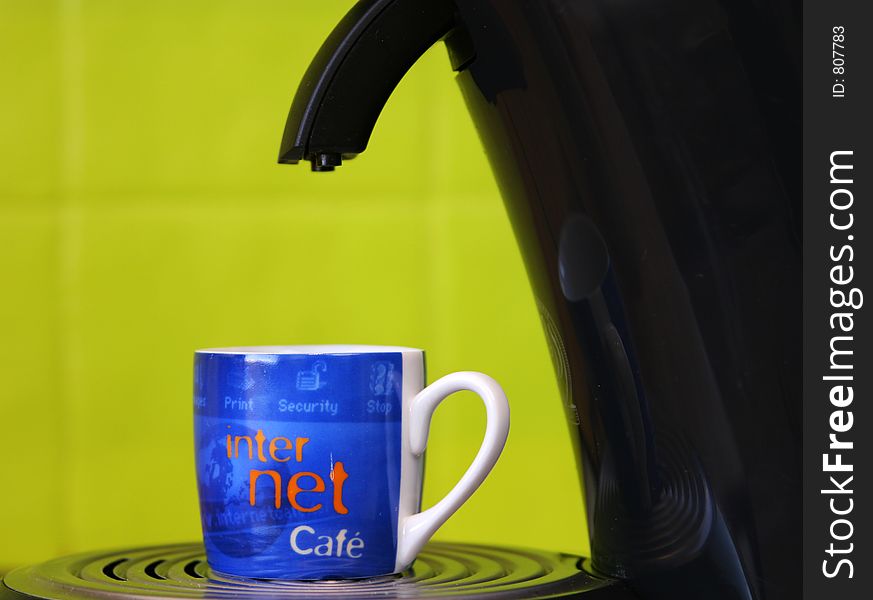 Coffeecup marked with internet and cafe standing on a coffemaker with a bright green background. Coffeecup marked with internet and cafe standing on a coffemaker with a bright green background